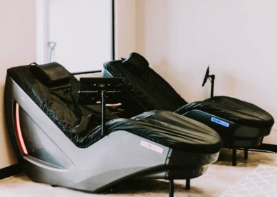 Two modern massage chairs, equipped with electronic control panels and black upholstery.