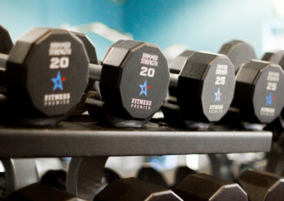 A row of hexagonal dumbbells labeled with weights on a rack at a gym, focusing on the 20-pound weights.