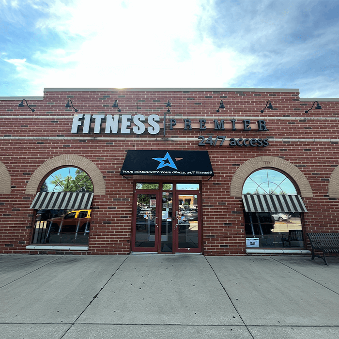 Front view of fitness premier gym building with red brick facade and large windows.